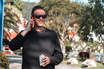 Fototapeta premium man using mobile phone and having coffee while walking