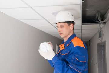a worker checks the smoke and fire sensor for malfunction