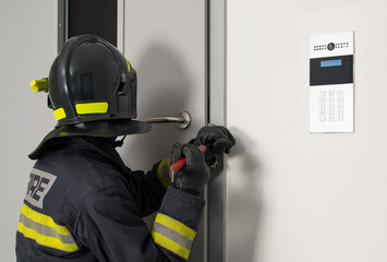 Fototapeta premium firefighter in protective uniform and helmet opens the closed door