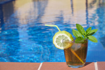 cocktail with lime an ice on the edge of a swimming pool