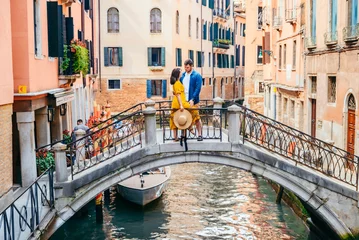 Fotobehang couple standing on the bridge crossing venice canals © phpetrunina14