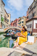 Tuinposter woman sitting on pond with view of venice canal eating pizza © phpetrunina14