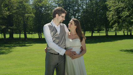 Blissful parents to be gaze at each other while gently caressing her baby bump