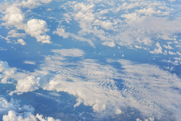 Fluffy sky clouds lit by afternoon sun, as seen from commercial airplane flying over