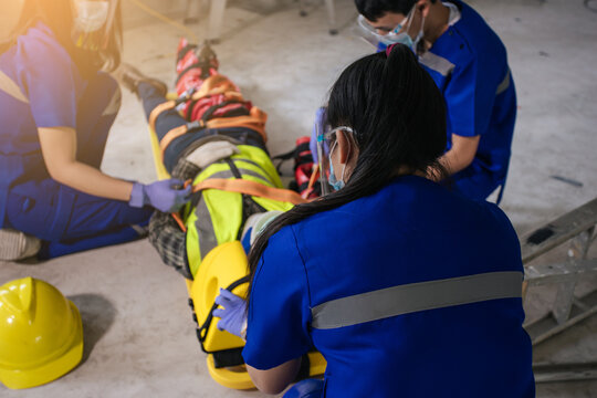 Paramedic woman and team first aid builder accident in site work. Team EMS paramedic first aid for head injuries. Employee accident in construction site work. Emergency service. First aid procedure.