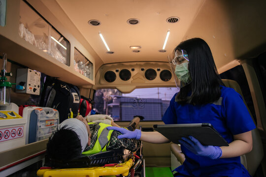 In epidemic crisis coronavirus (COVID-19), Asian female paramedic provide medical help to injured accident on ambulance in transfer patient.