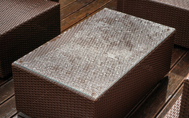Simple brown artificial rattan garden furniture, top covered with raindrops, closeup detail