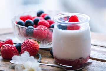 yoghurt with raspberries and blueberries on wooden background