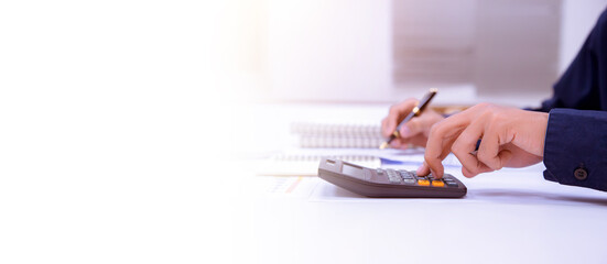 businessman working on a desk with a calculator to calculate the numbers finance accounting year...