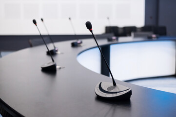 Close-up of microphones in an empty meeting room at a press conference.