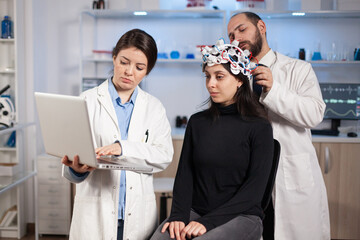 Specialist neurologist doctor taking notes on laptop asking patient's symptoms adjusting high tech...