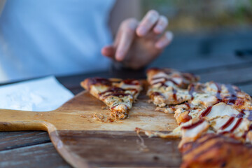 person eating a pizza with bbq sauce at an outdoor cafe