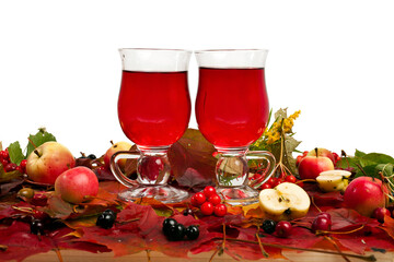 Mulled wine in the glass cups on a fallen autumn leaves background with berries, apples and...