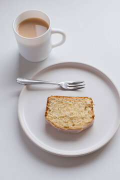 a simple and minimal photo of a slice of lemon drizzle drinks and a cup of tea or coffee 