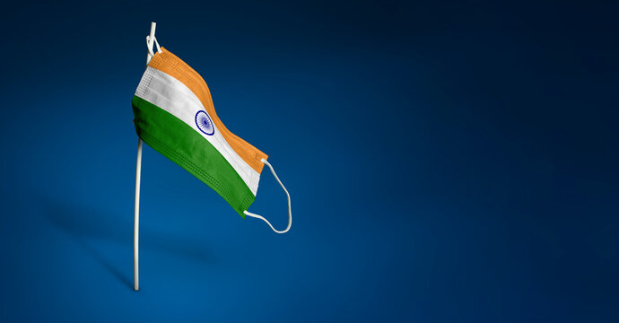 India mask on dark blue background. Waving flag of India painted on medical mask on pole. Concept of The banner of the fight against the epidemic coronavirus COVID-19. Copy space