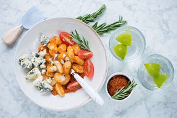 Potato gnocchi with sun dried tomato pesto and gorgonzola, flatlay over light-grey marble background