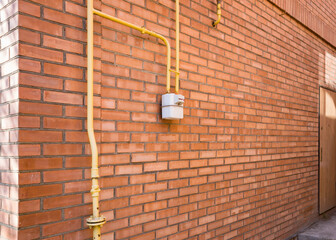 Gas meter and pipes, valves on the bricks wall of a private house.