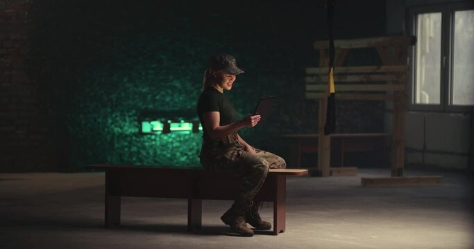 Military woman making video call on bench in gym
