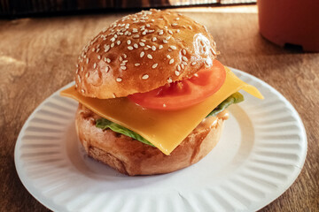 Burger in paper packaging close-up. Food in a fast food restaurant. Macro photo of burger ingredients with meat and vegetables