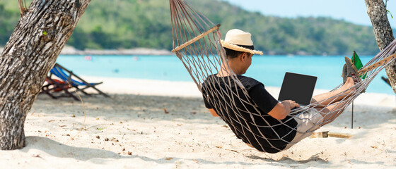 Lifestyle freelance man using laptop working and relax on the beach.  Asian people on hammock...
