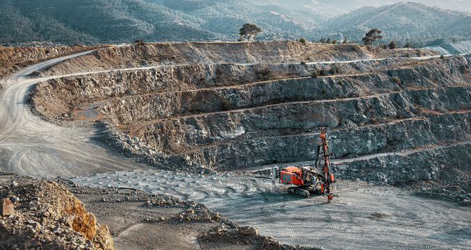 Industrial landscape with red stone crusher machine in gravel quarry