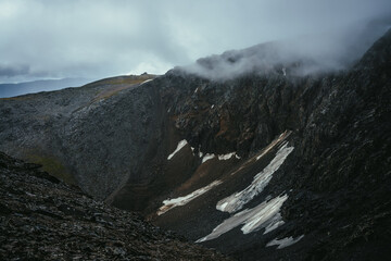 Dark atmospheric landscape on edge of abyss in highlands. Dangerous mountains and abyss in overcast...