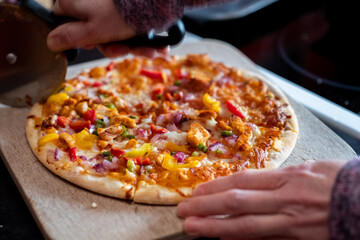 Close up and selective focus of a home cooked thin crust sweet chilli chicken pizza on a wooden...