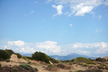 Wonderful landscape, blue sky with light clouds, a line of mountains in the background. In the foreground is a desert landscape with little vegetation.