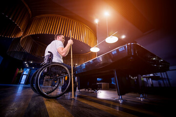 Fototapeta na wymiar Adult man with disability in a wheelchair play billiards in the club