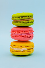 three multicolored macaron cakes on a blue paper background
