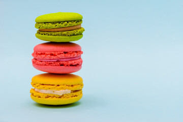 three multicolored macaron cakes on a blue paper background