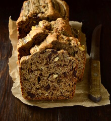 Banana bread with walnut and chocolate on dark wooden background