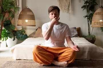 Caucasian mature man practicing yoga sitting, making Alternate Nostril Breathing
