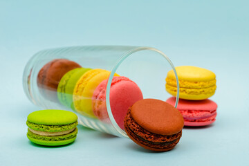 several color macaron cakes in a glass cup on a blue background