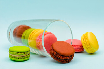 several color macaron cakes in a glass cup on a blue background
