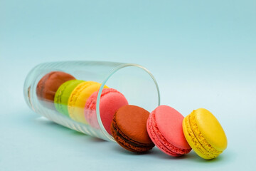several color macaron cakes in a glass cup on a blue background