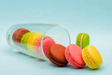several color macaron cakes in a glass cup on a blue background
