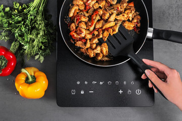 Woman is preparing an Asian dish on an induction stove in the kitchen at home. French meat with...
