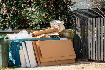 Household miscellaneous rubbish items piled outside residential building for council waste collection.