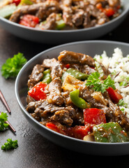 Stir fry Chinese pepper beef steak with onion, red and green bell pepper, rice in bowl