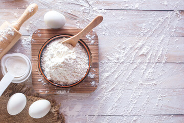Homemade flour recipe ingredients (Eggs, flour, sugar) and rolling pin on a wooden table, view from above