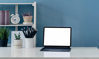Creative workspace with blank screen computer on white table and blue wall.