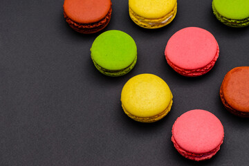 different multicolored macaron cakes on a black background