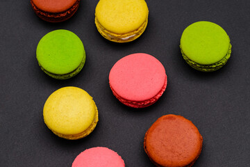 different multicolored macaron cakes on a black background