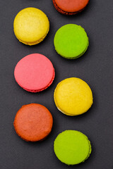different multicolored macaron cakes on a black background