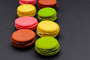 Fototapeta na wymiar different multicolored macaron cakes on a black background