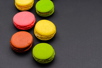 several multicolored macaron cakes on a black background