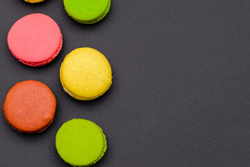 different multicolored macaron cakes on a black background