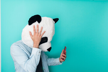 Worried man in panda mask reading bad news on mobile phone