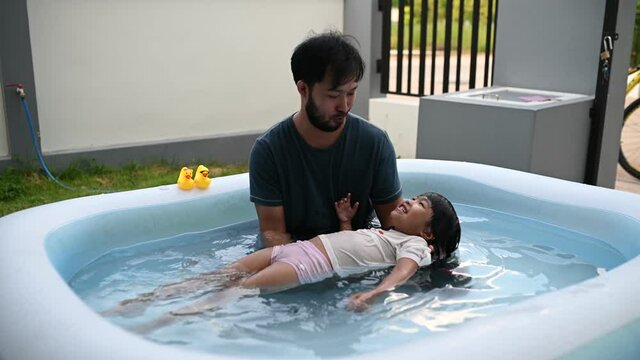 Father day concept,Asian dad and daughter use time together at home,Play in the inflatable pool